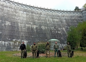 Zdjęcie grupowe 5 funkcjonariuszy SG z psami służbowymi w tle Zapora Leśniańska