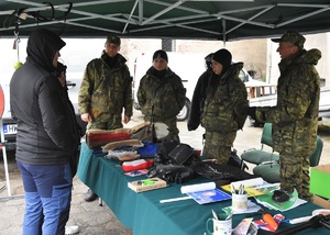 Kobieta i mężczyzna oraz czterech funkcjonariuszy SG przy stoliku ze sprzętem służbowym SG