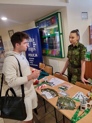 Funkcjonariuszka SG ze studentem Uniwersytetu Wrocławskiego przy stoliku promocyjnym