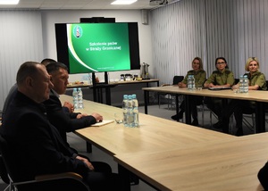 Funkcjonariuszki SG oraz przedstawiciele OBWE oraz Republiki Kirgistanu w sali odpraw Ośrodka. W tle tablica multimedialna.