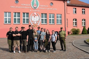 Zdjęcie grupowe uczestników wizyty z funkcjonariuszami SG na tle budynku Ośrodka