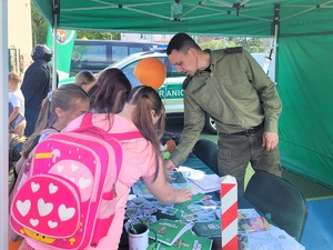 Funkcjonariusz SG oraz uczniowie szkoły przy stoisku promocyjnym