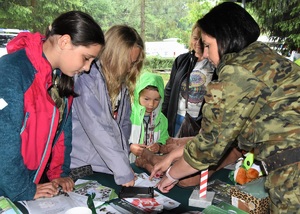 Funkcjonariuszka SG oraz dzieci przy stoisku promocyjnym SG