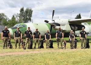 Zdjęcie grupowe funkcjonariuszy SG z pasami służbowymi. W tle samolot