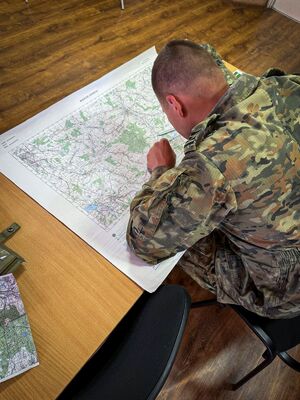 Funkcjonariusz SG pochylony nad mapą na sali wykładowej