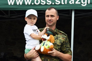 Funkcjonariusz SG  oraz chłopiec z maskotką SG
