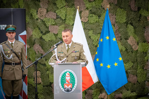 Komendant Ośrodka OSS SG stojący przy mównicy, w tle flaga Polski i UE