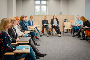 Jedenastu uczestników warsztatów siedzący na krzesłach