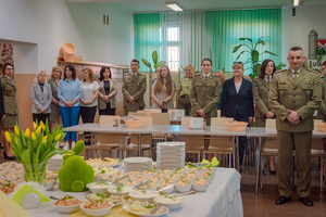 Funkcjonariusze i pracownicy stojący wokół udekorowanego stołu